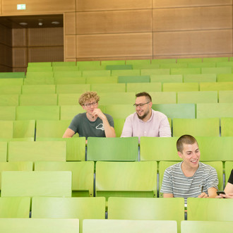 Vier Studierende sitzen in einem Hörsaal.