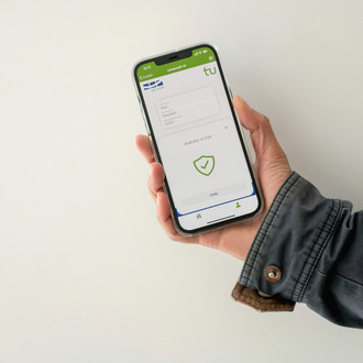 Eine Hand hält ein Smartphone. Darauf ist die CampusID und ein grüner Haken abgebildet.